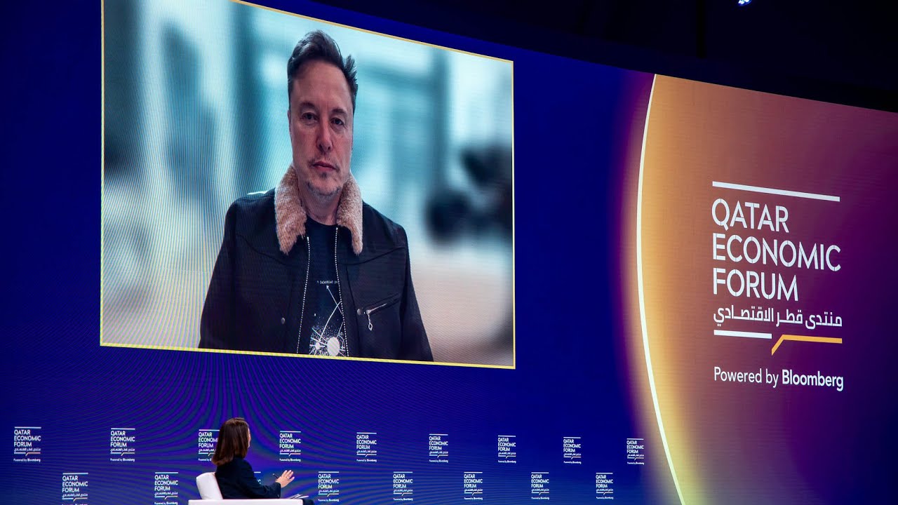 Elon Musk speaking by video at the Qatar Economic Forum, with Bloomberg event branding beside him
